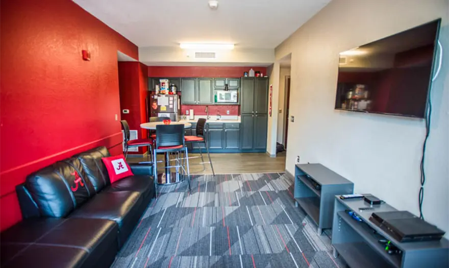 Bryant hall living room with a sectional, dining table with chairs, side tables, and a tv