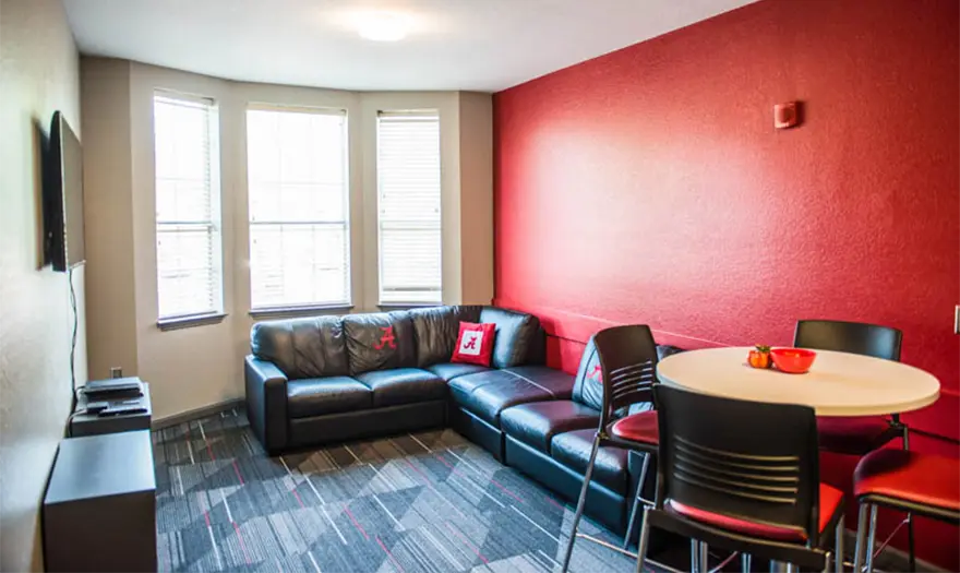Bryant hall living room with a sectional, dining table with chairs, side tables, and a tv