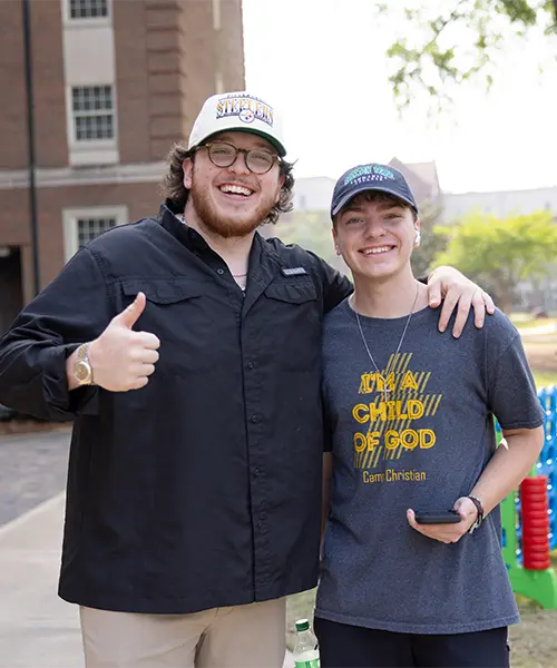 Resident advisor smiling and holding a thumbs up while standing by a resident