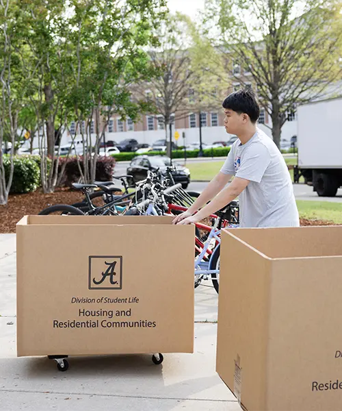 Ready crew student worker pushing moving carts into residence hall to get ready for move-out
