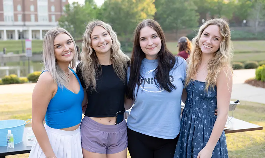 Group of 4 UA Housing residents standing together in front of Palmer Lake smiling