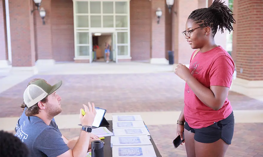 Students standing at check-in table smiling