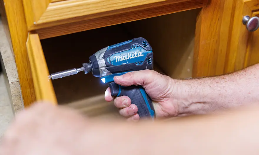 UA Facilities and Grounds employee fixing a kitchen cabinet